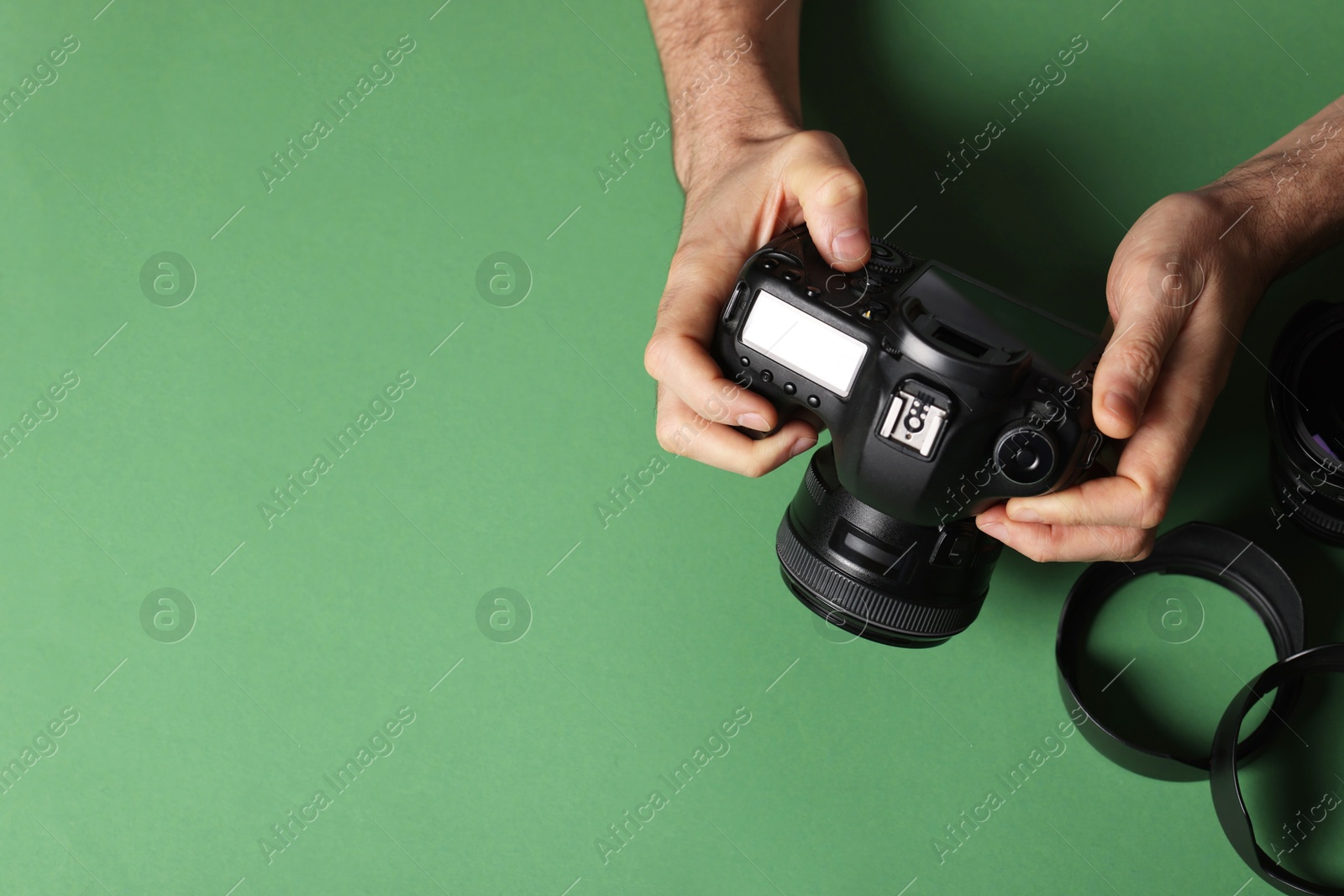 Photo of Photographer with professional camera and equipment on green background, top view. Space for text