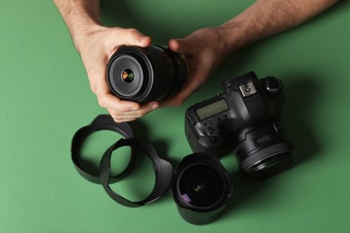 Photo of Photographer with professional camera and equipment on green background, top view