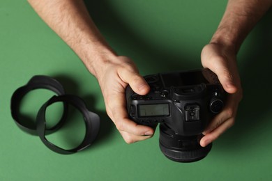 Photo of Photographer with professional camera and equipment on green background, top view