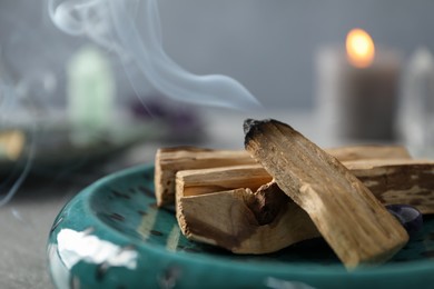 Photo of Smoldering palo santo stick on table, closeup