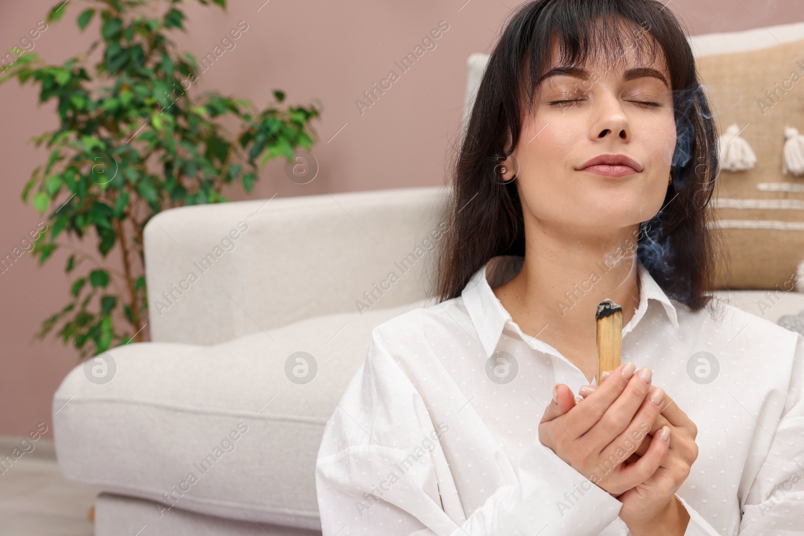 Photo of Woman with smoldering palo santo stick at home