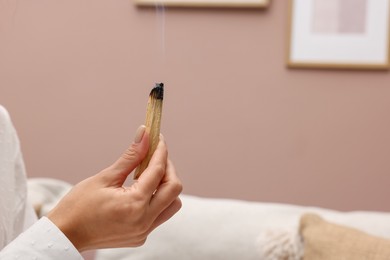 Photo of Woman with smoldering palo santo stick at home, closeup. Space for text