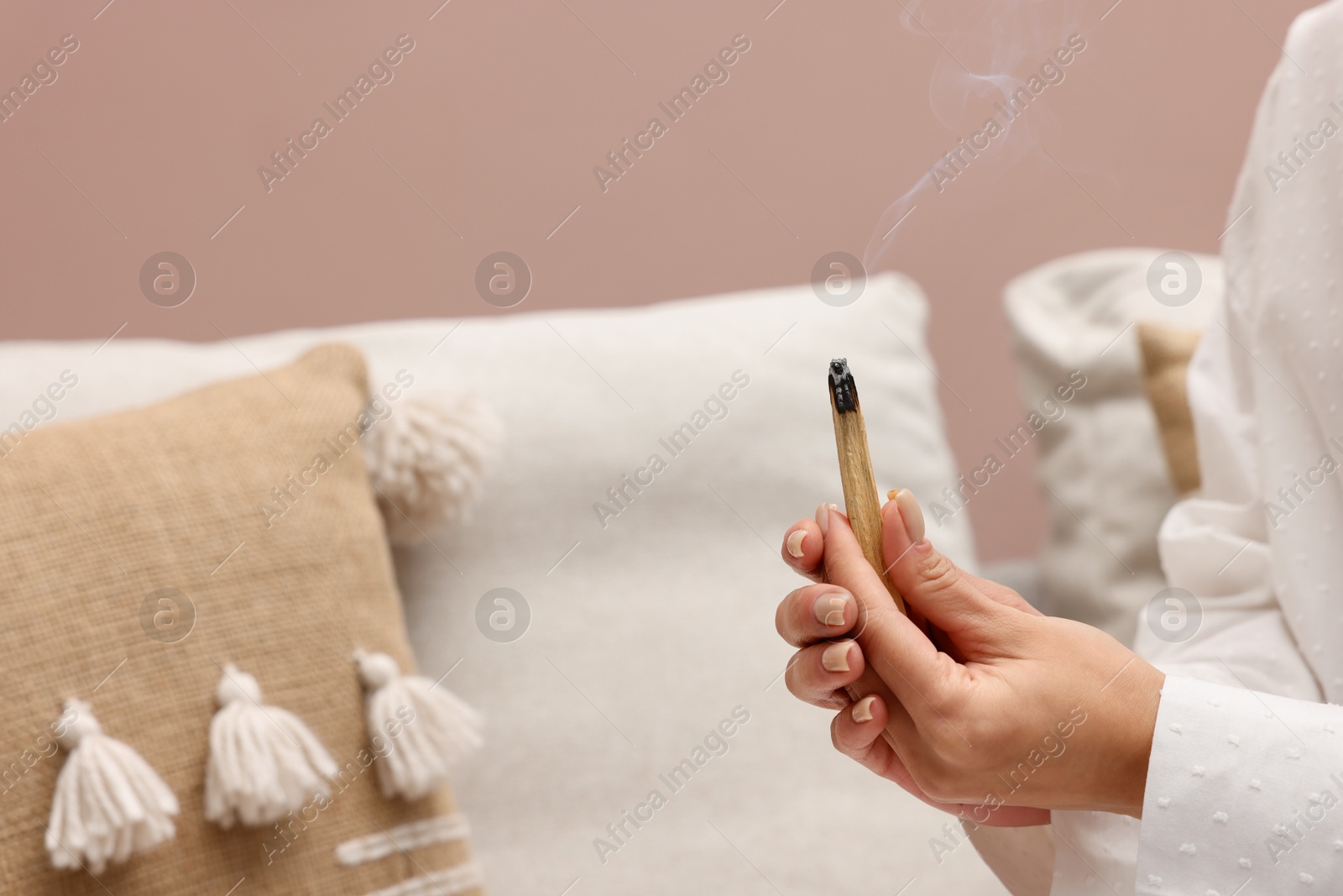 Photo of Woman with smoldering palo santo stick at home, closeup. Space for text