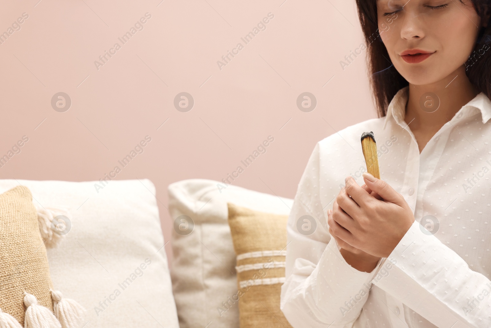 Photo of Woman with smoldering palo santo stick at home, space for text