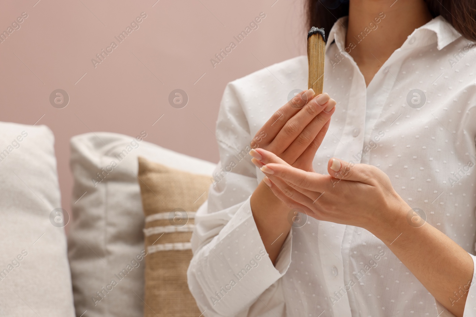 Photo of Woman with smoldering palo santo stick at home, closeup. Space for text