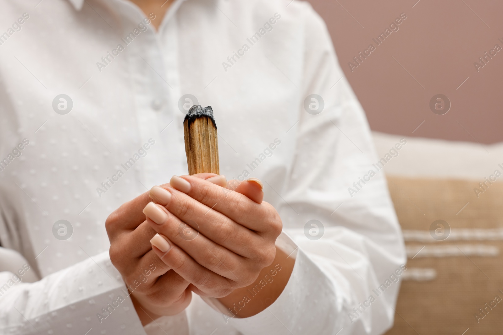 Photo of Woman with smoldering palo santo stick at home, closeup