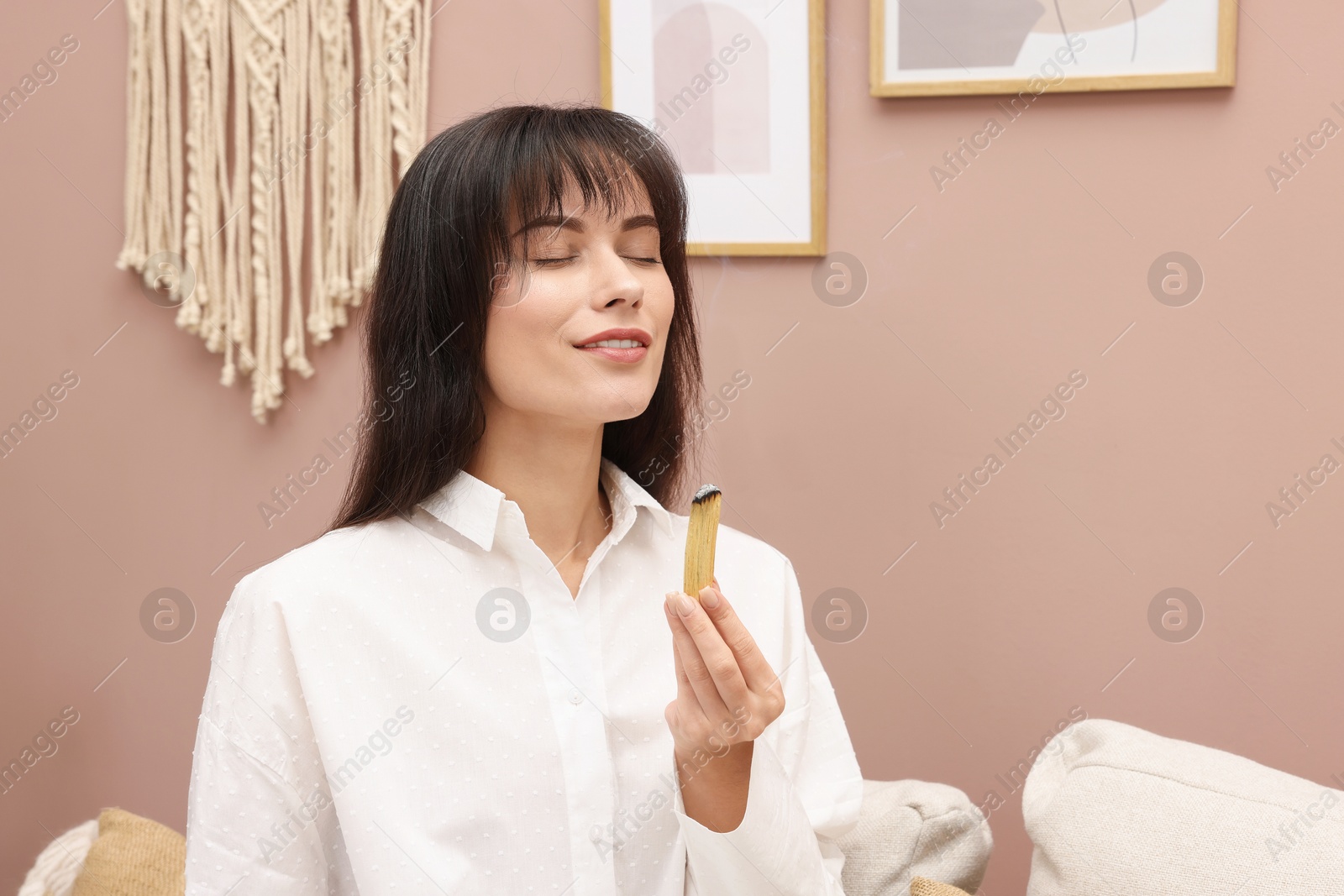 Photo of Woman with smoldering palo santo stick at home, space for text