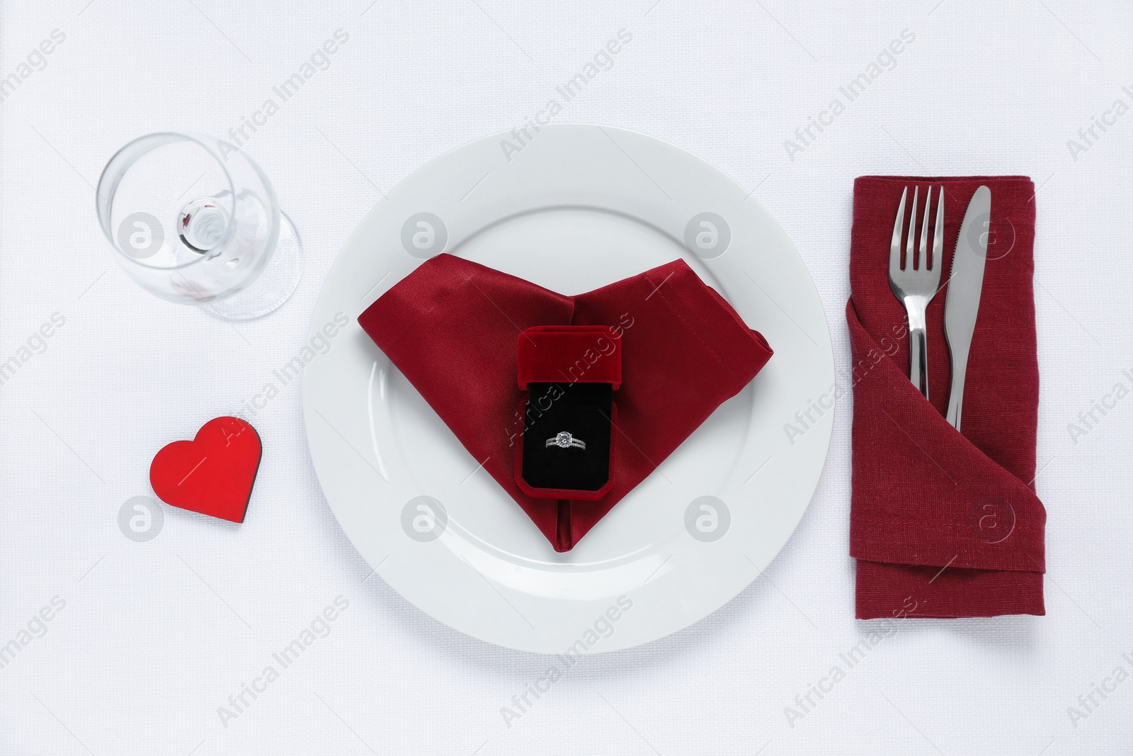 Photo of Beautiful engagement ring and setting for romantic dinner on white background, top view