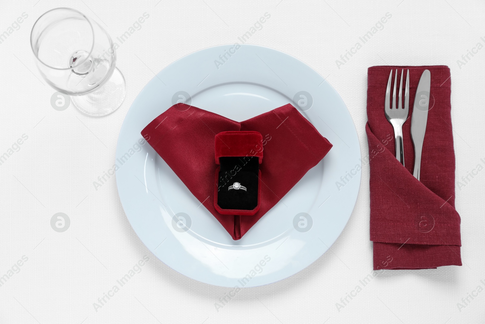 Photo of Beautiful engagement ring and setting for romantic dinner on white background, top view