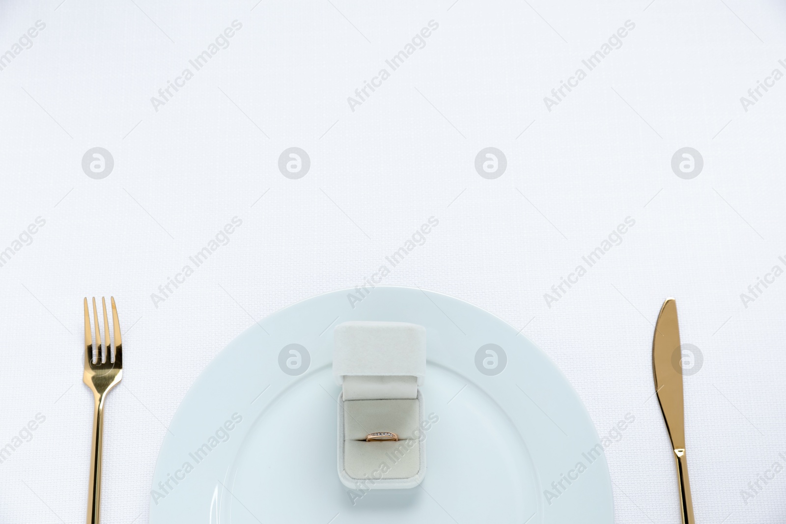 Photo of Beautiful engagement ring and setting for romantic dinner on white background, top view. Space for text