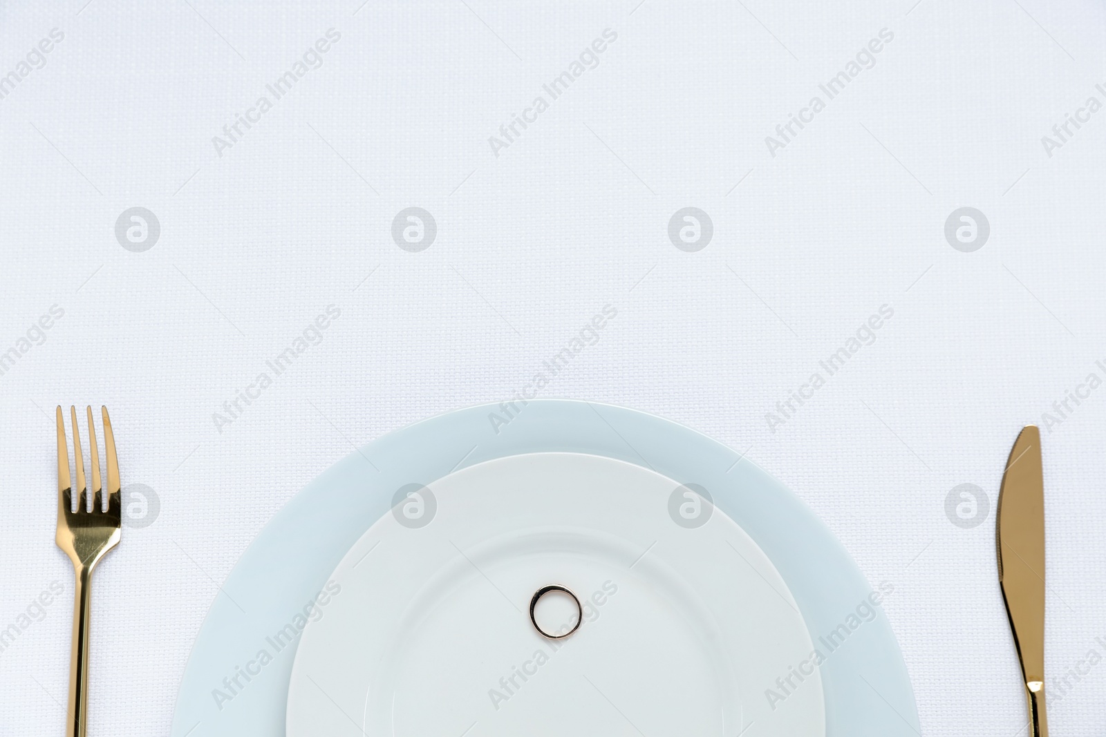 Photo of Beautiful engagement ring and setting for romantic dinner on white background, top view. Space for text