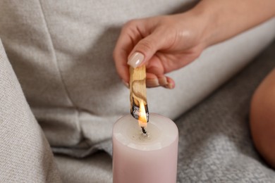 Photo of Woman lighting palo santo stick at home, closeup