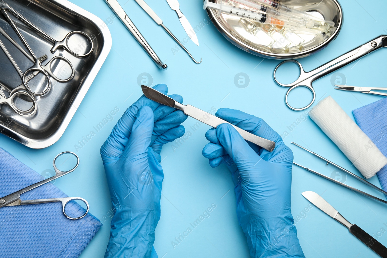 Photo of Doctor with different surgical tools on light blue background, top view