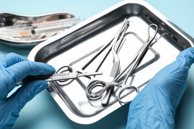 Photo of Doctor with different surgical tools on turquoise background, closeup