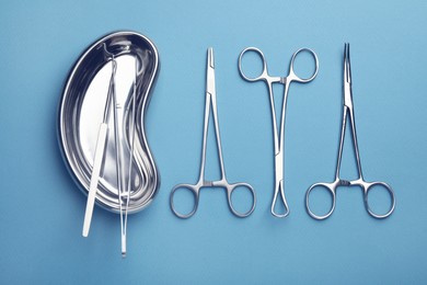 Photo of Different surgical tools on light blue background, flat lay