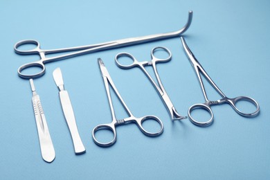 Photo of Different surgical tools on light blue background, closeup