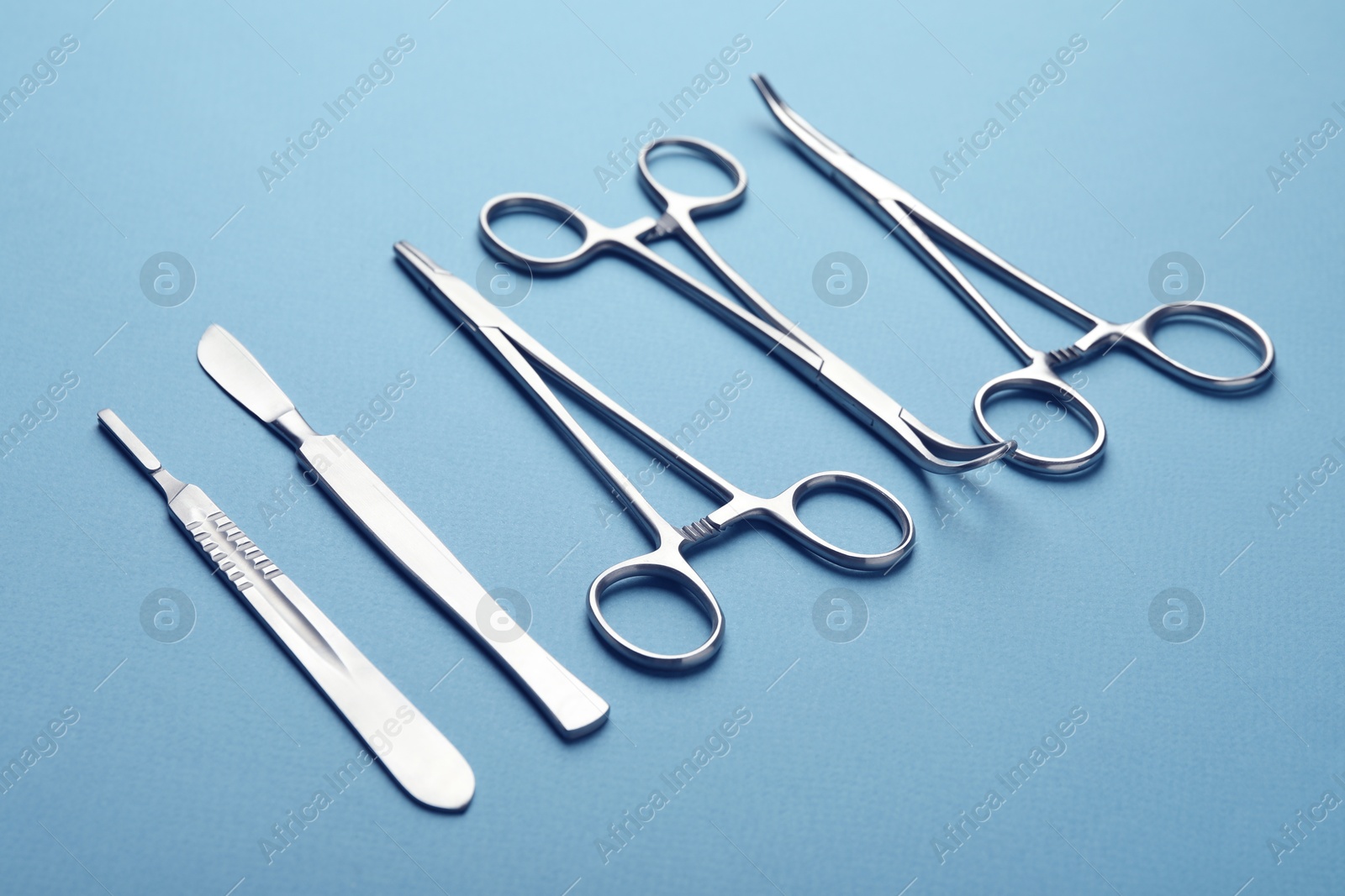 Photo of Different surgical tools on light blue background, closeup