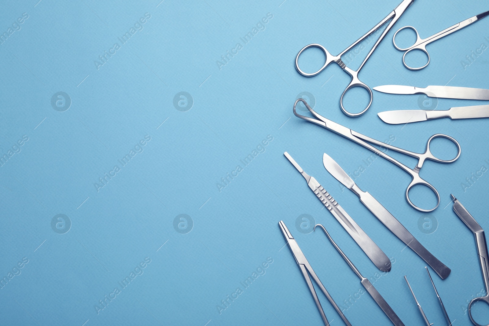 Photo of Different surgical tools on light blue background, flat lay. Space for text