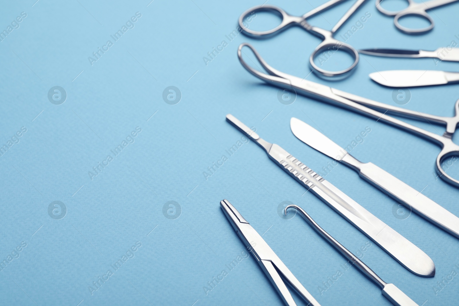 Photo of Different surgical tools on light blue background, closeup. Space for text