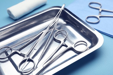 Photo of Different surgical tools on light blue background, closeup