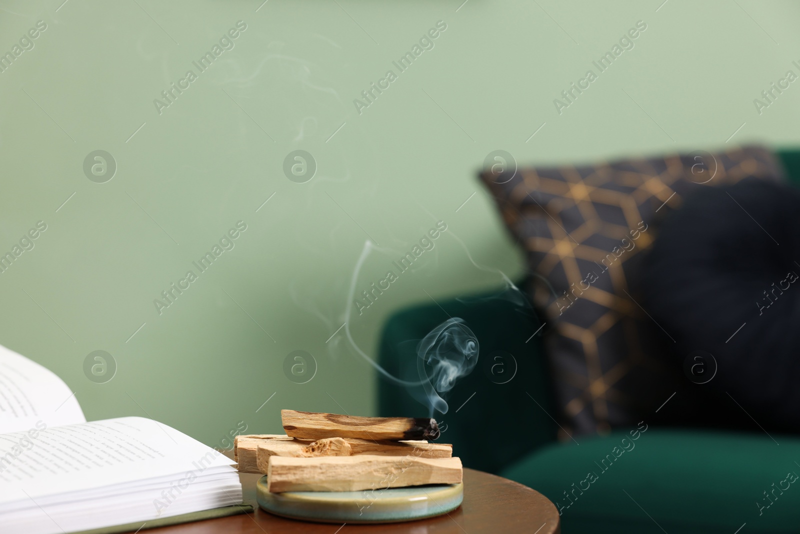 Photo of Palo santo sticks and book on table indoors, space for text