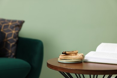 Photo of Palo santo sticks and book on table indoors, space for text