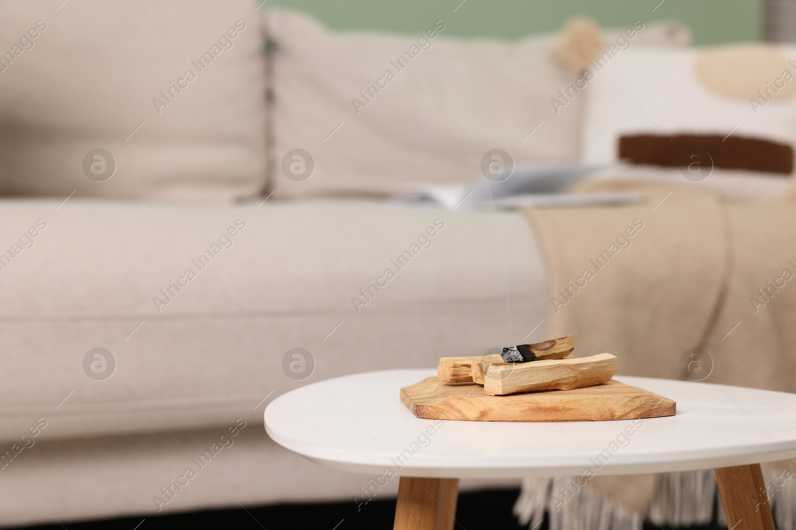 Photo of Palo santo sticks and burnt one on white table indoors, space for text