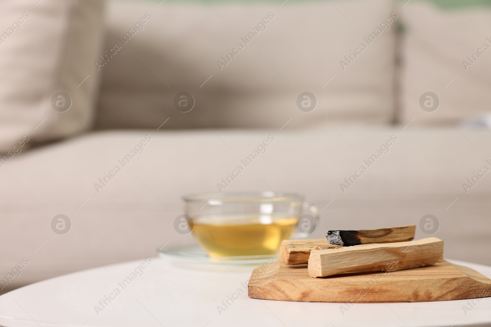 Photo of Palo santo sticks and burnt one on white table indoors, space for text