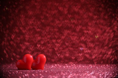 Photo of Romantic decor. Small hearts on shiny pink glitter and heart shaped lights, space for text. Bokeh effect