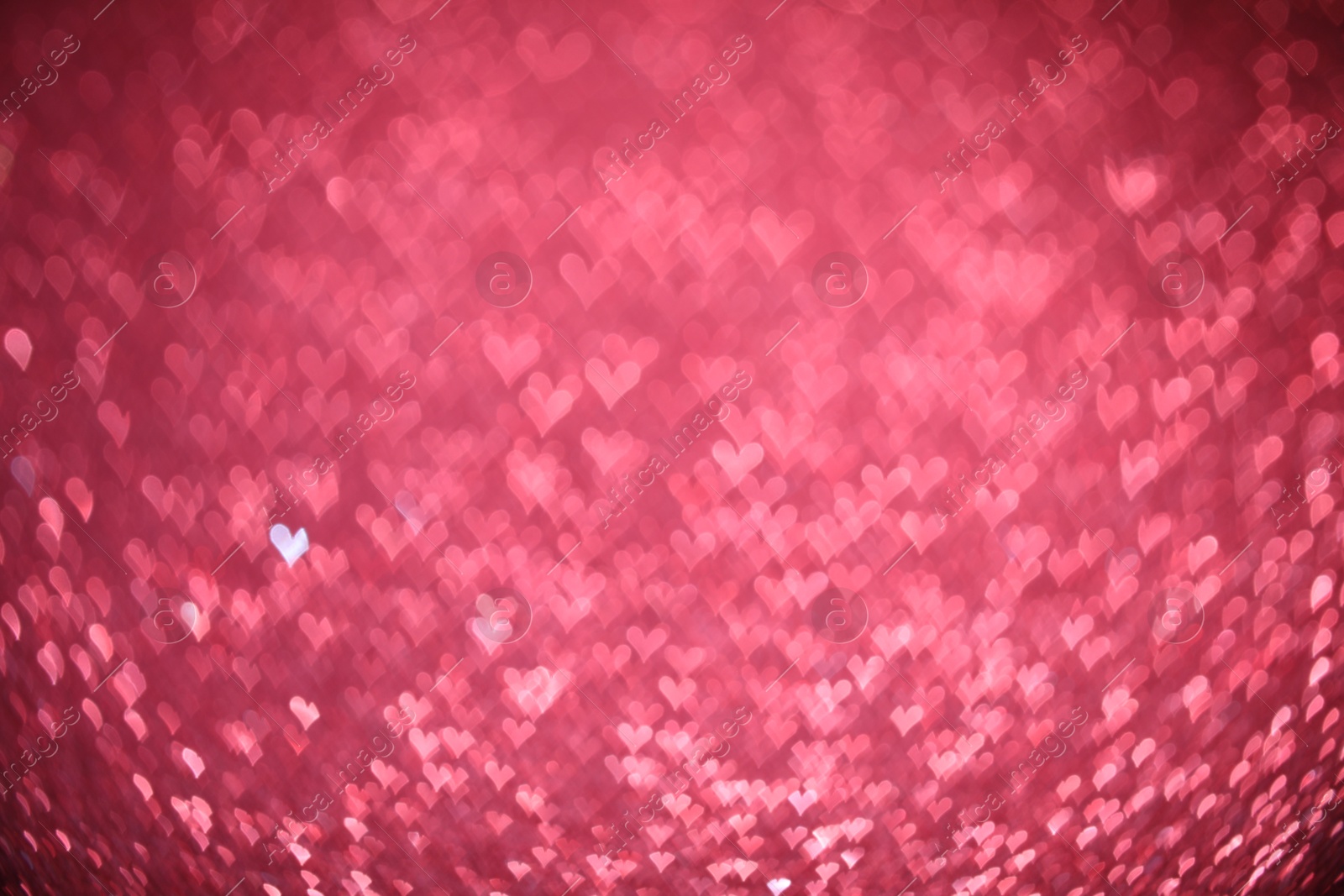 Photo of Romantic decor. Blurred view of heart shaped lights on pink background, bokeh effect