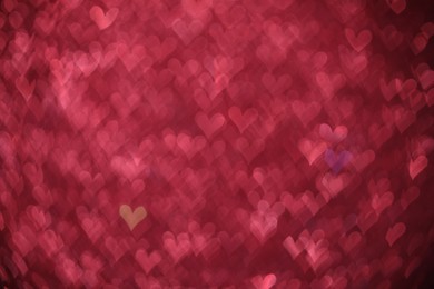 Photo of Romantic decor. Blurred view of heart shaped lights on pink background, bokeh effect