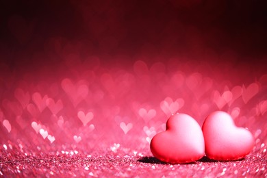 Photo of Romantic decor. Small hearts on shiny pink glitter and heart shaped lights, space for text. Bokeh effect