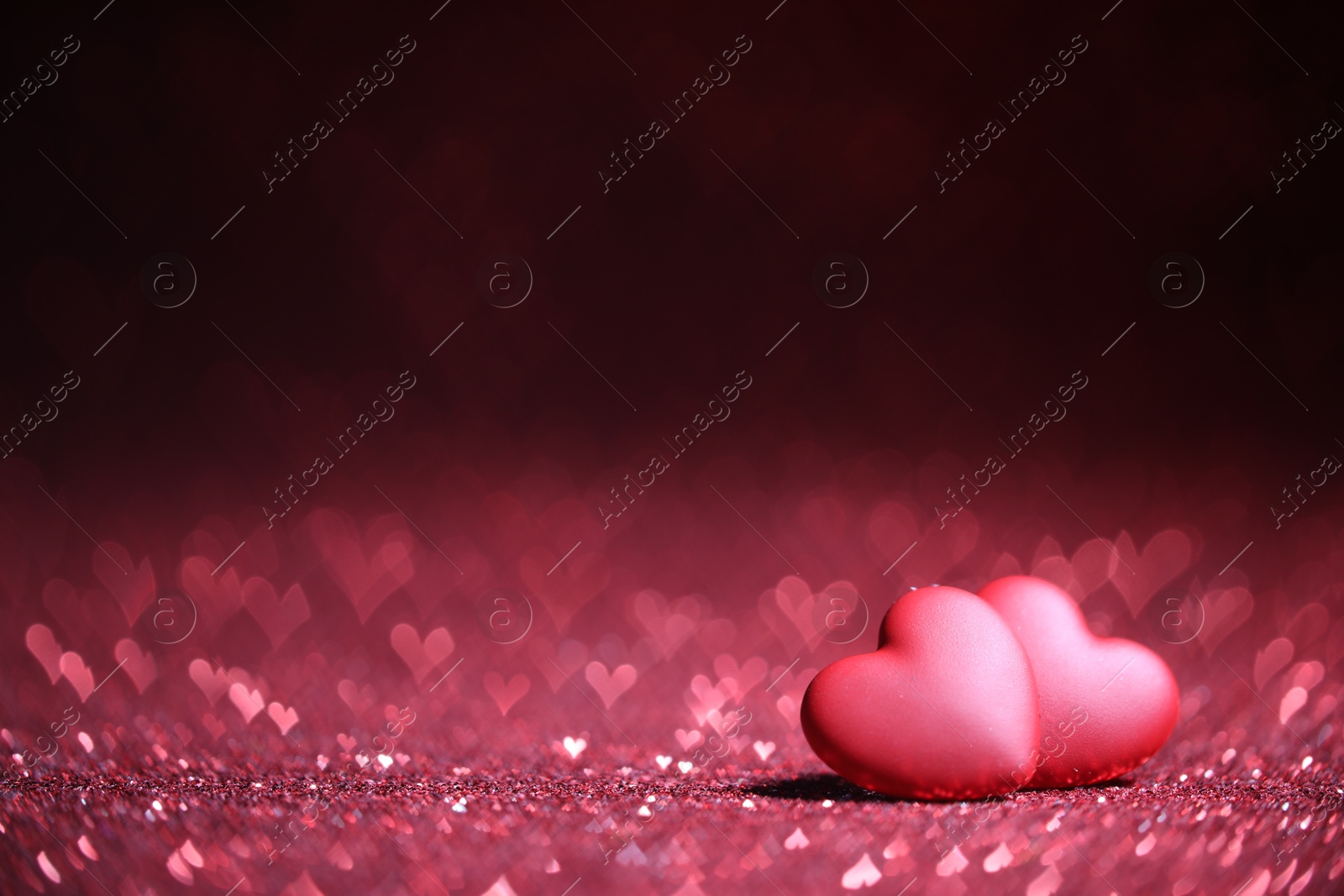 Photo of Romantic decor. Small hearts on shiny pink glitter and heart shaped lights, space for text. Bokeh effect