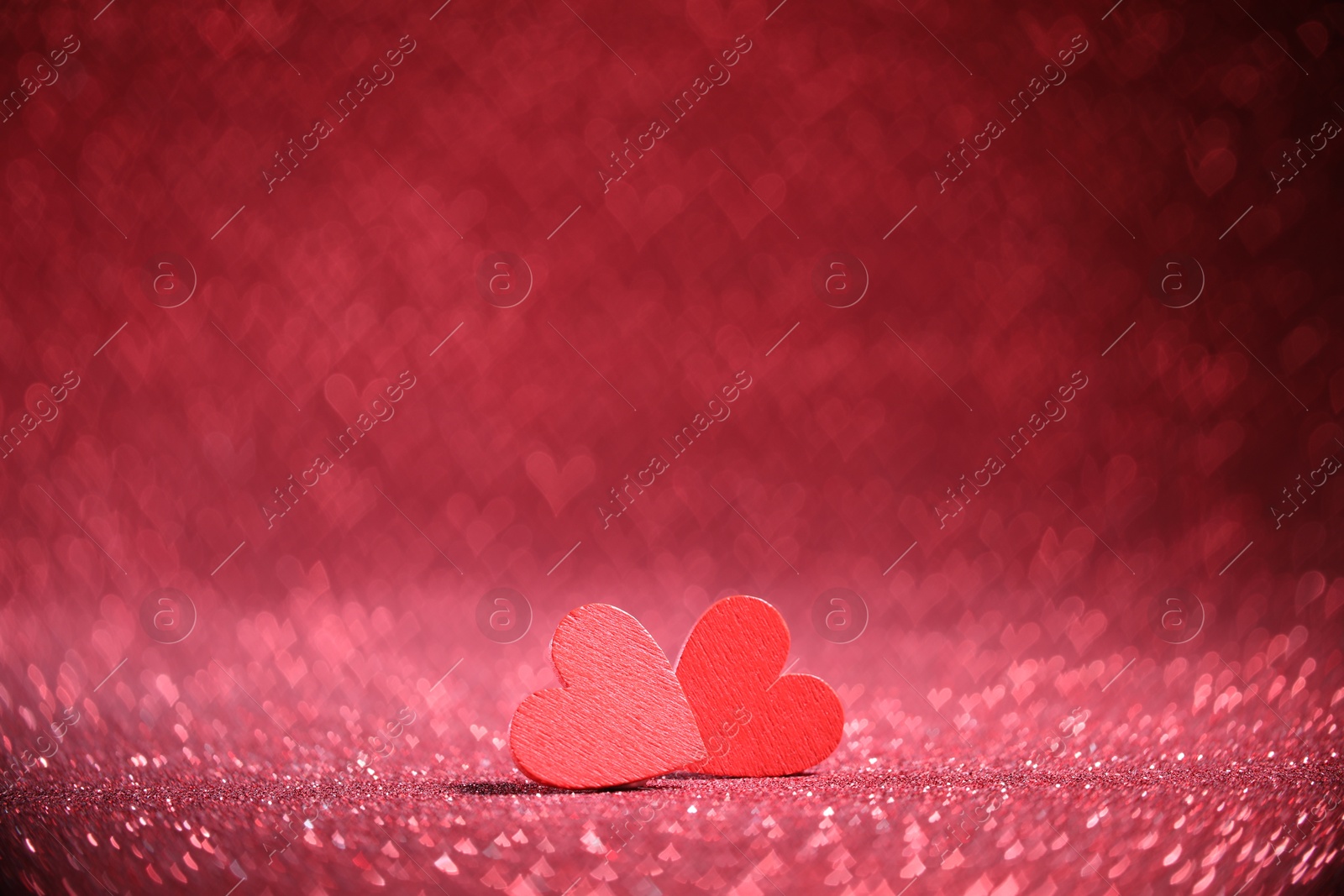 Photo of Romantic decor. Wooden hearts on shiny pink glitter and heart shaped lights, space for text. Bokeh effect