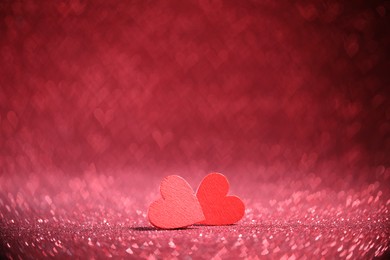 Photo of Romantic decor. Wooden hearts on shiny pink glitter and heart shaped lights, space for text. Bokeh effect