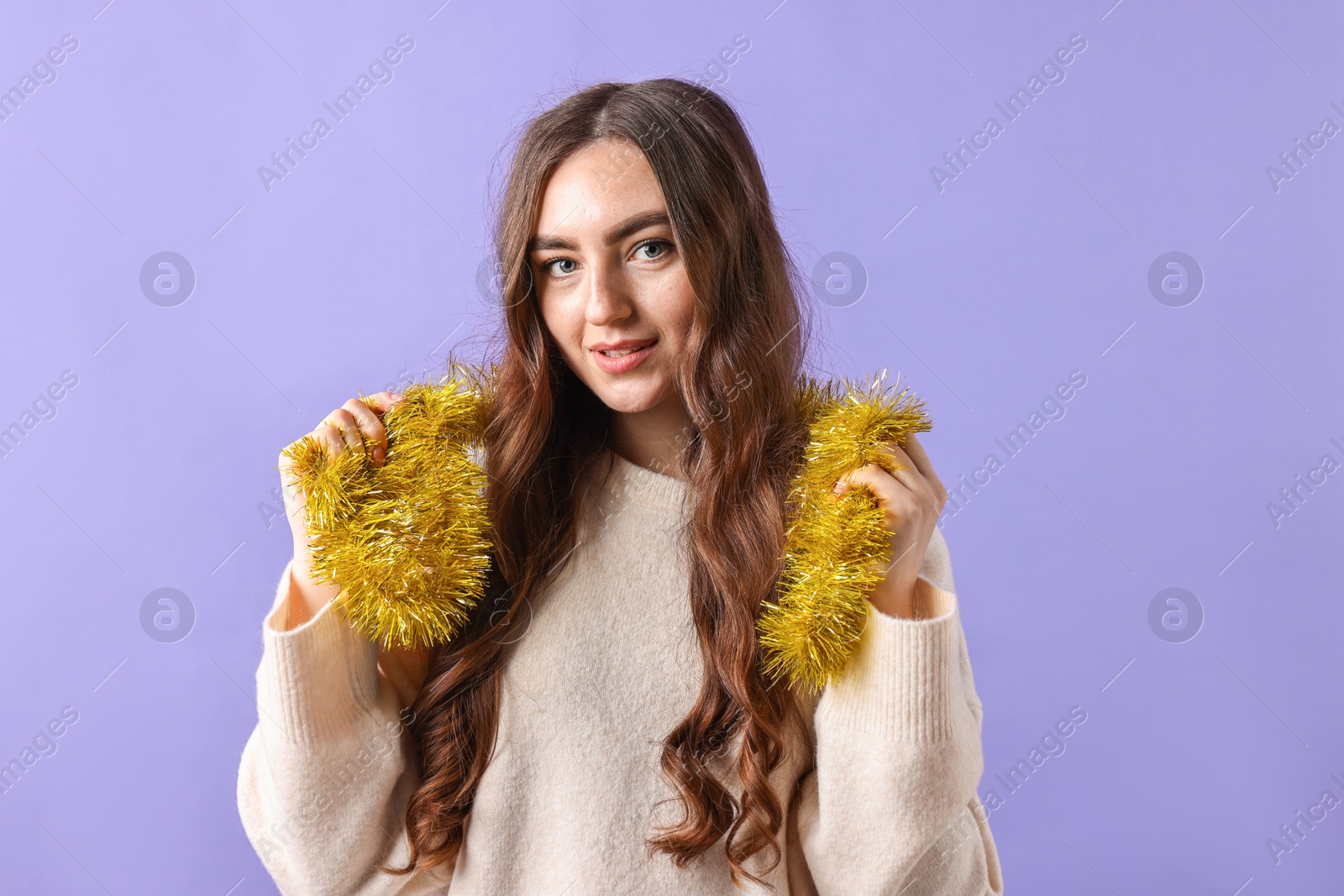 Photo of Beautiful young woman with tinsel on purple background