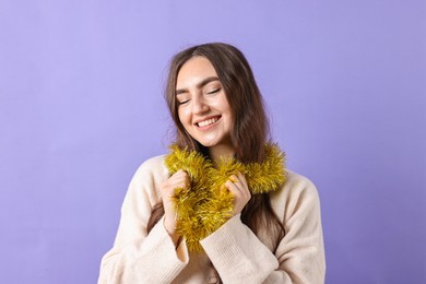 Photo of Happy young woman with tinsel on purple background