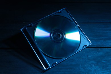 Photo of One compact disc in jewel case on wooden background, closeup