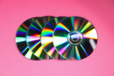 Photo of Many shiny compact discs on pink background, top view