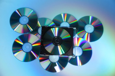 Photo of Many compact discs on light blue background, top view