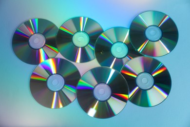 Photo of Many compact discs on light blue background, top view