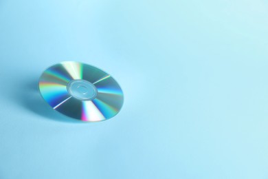 Photo of One shiny compact disc on light blue background. Space for text