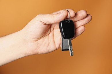 Photo of Man with car key and keychain on orange background, closeup