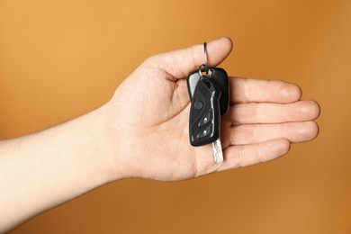 Photo of Man with car keys on orange background, closeup