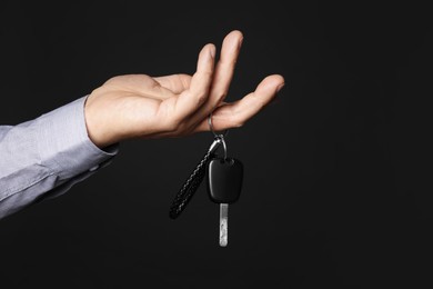 Photo of Man with car key and keychain on black background, closeup. Space for text