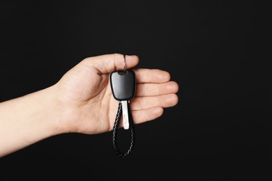 Photo of Man with car key and keychain on black background, closeup. Space for text