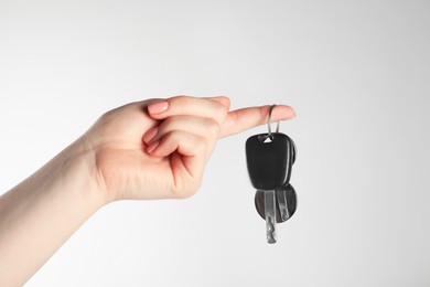 Photo of Woman with car key and keychain on light grey background, closeup