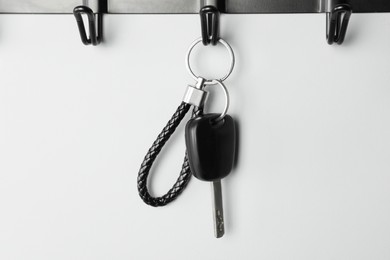 Car key on hanger against grey wall