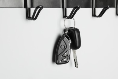 Photo of Car keys on hanger against light wall, closeup