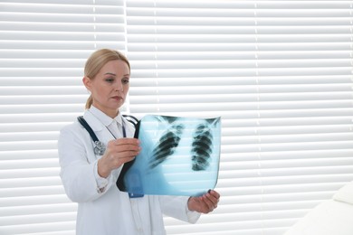 Photo of Doctor examining x-ray image of lungs in clinic, space for text